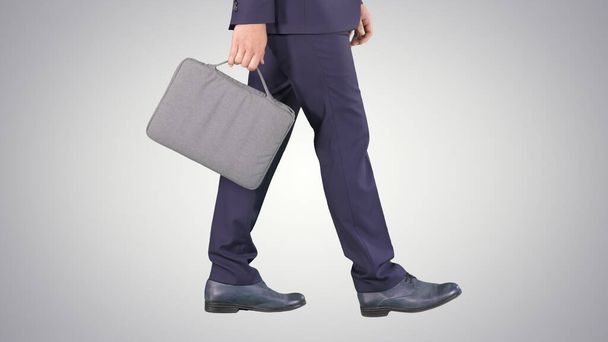 Handsome businessman in a suit walks with a briefcase on gradien - Fotó, kép
