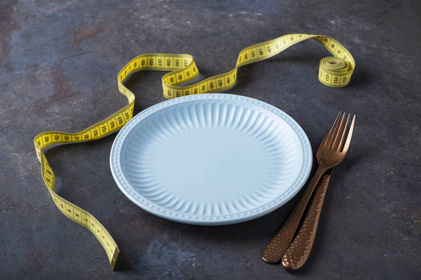 Κενό πιάτο με πιρούνι και μαχαίρι κοντά σε μεζούρα. Έννοια απώλειας βάρους. Τρόπος ζωής - Φωτογραφία, εικόνα
