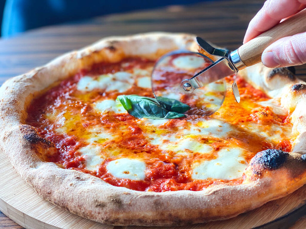 Gros plan main de l'homme coupe pizza Margarita. - Photo, image