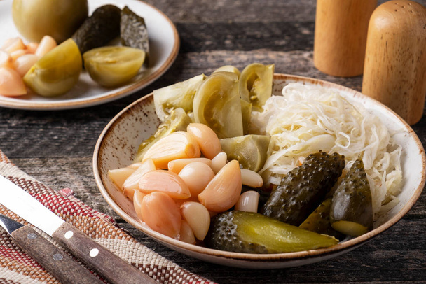  Fermented cabbages, cucumbers, tomatoes and garlic on a plate. Cold snack - Zdjęcie, obraz