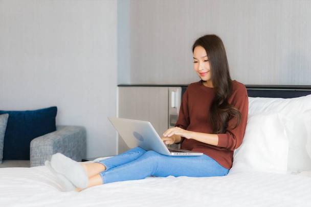 Retrato hermosa joven mujer asiática uso de ordenador portátil en la cama en el interior del dormitorio - Foto, imagen