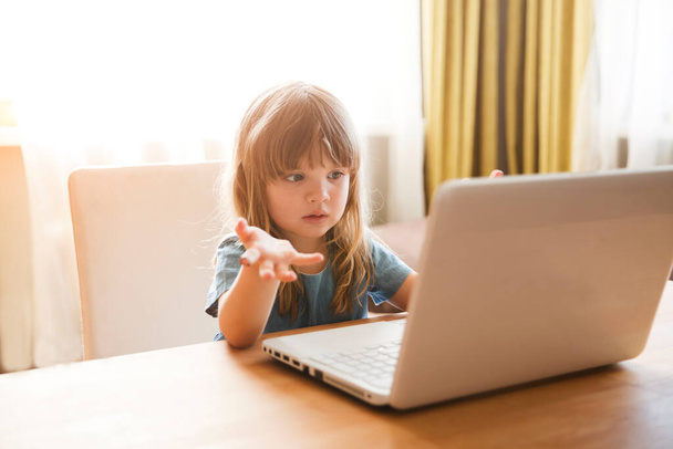 Child girl is using a laptop and communicates on the Internet at home. Training online. quarantine. Corona Virus. kid study at home. - Photo, Image