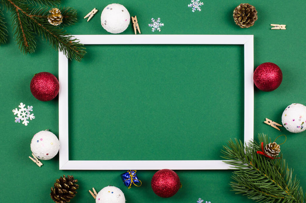 Λευκό πλαίσιο με κλαδιά ελάτης και παιχνίδια της Πρωτοχρονιάς σε πράσινο φόντο. Χριστουγεννιάτικη κάρτα - Φωτογραφία, εικόνα