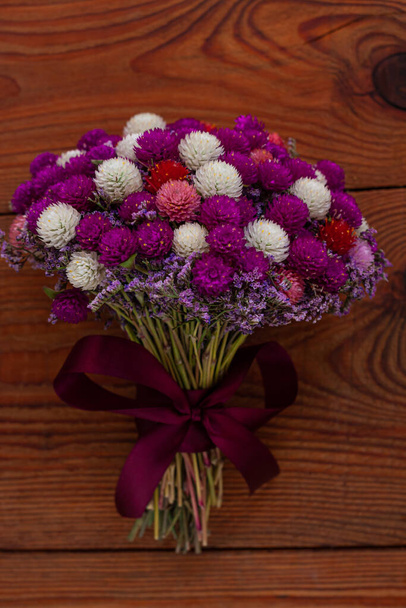 Esküvői kreatív szárított virágok csokor fa háttér. Vidéki lila fehér Gomphrena virágcsokor. Egyszerű öko dekoráció. Valentin nap romantikus virágzó ajándék. Virágos kézműves foglalkozások - Fotó, kép