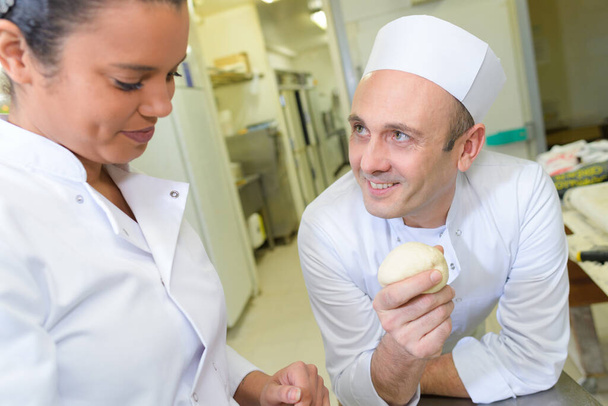 professional chef showing dough to female trainee - Фото, зображення