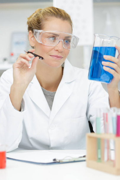 woman lab assistant holding a empty tube and watch - Photo, Image