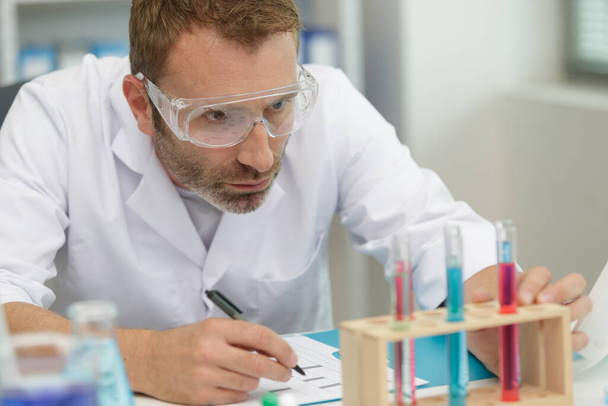 concentrated male researcher holding a test tube - Zdjęcie, obraz