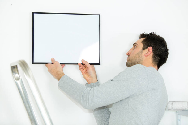 man adjusting the angle of wall frame - Фото, зображення