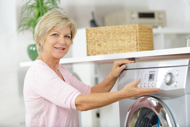 woman next to a washing machine - Foto, afbeelding