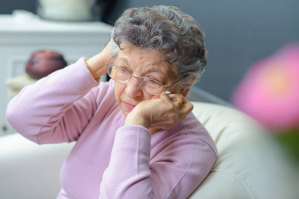 Elderly lady holding her head in her hands - Foto, Imagen
