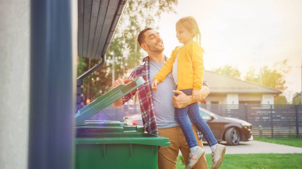 Happy Father Holding a Young Girl and Threw Away a Food Waste into the Trash. They Use Correct Garbage Bins Because This Family is Sorting Waste and Helping the Environment. - 写真・画像