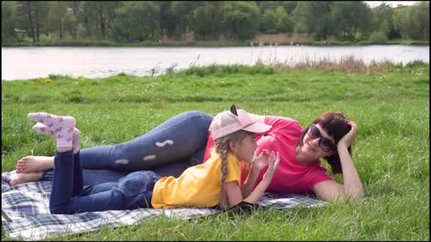 Мама з дочкою веселяться, розмовляючи на фоні річки.. - Кадри, відео