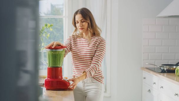 Beautiful Young Female Preparing a Healthy Green Smoothie in a Blender. Authentic Stylish Kitchen with Healthy Vegetables. Natural Clean Products from Organic Farming Used to Make Drinks. - Photo, image