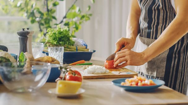 Close Up Shot of a Man Chopping a Tomato with a Sharp Kitchen Knife. Preparing a Healthy Organic Salad Meal in a Modern Kitchen. Natural Clean Diet and Healthy Way of Life Concept. - Photo, Image
