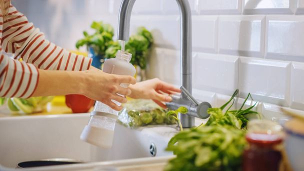 Close Up Shot of a Woman Filling a Reusable Plastic Bottle with Clean Filtered Tap Water. Using Sports Bottle for H2O in a Modern Kitchen. Natural Clean Diet and Healthy Way of Life Concept. - Foto, Imagem