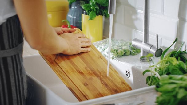 Close Up Shot of a Person Washing a Chopping Board with a Cleaning Liquid Under Tap Water. Using Dishwasher in a Modern Kitchen. Natural Clean Home and Healthy Way of Life Concept. - Photo, image