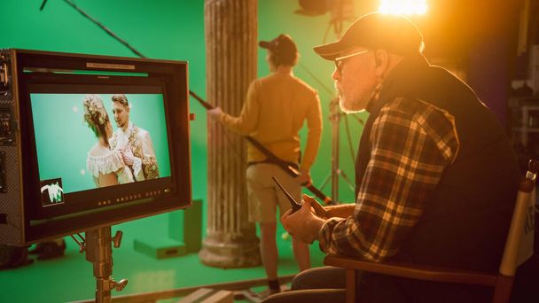 Director Looks at Display Controls Shooting Period Drama Movie. Green Screen CGI Scene with Actors Wearing Renaissance Costumes. Crew Shooting High Budget Movie. Side View - Photo, image