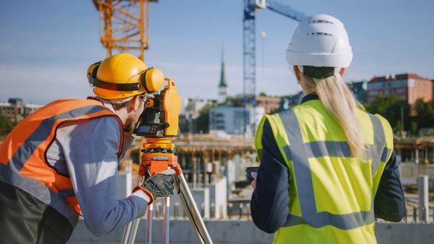 Construction Worker Using Theodolite Surveying Optical Instrument for Measuring Angles in Horizontal and Vertical Planes on Construction Site. Engineer and Architect Using Tablet Next to Surveyor. - Fotó, kép