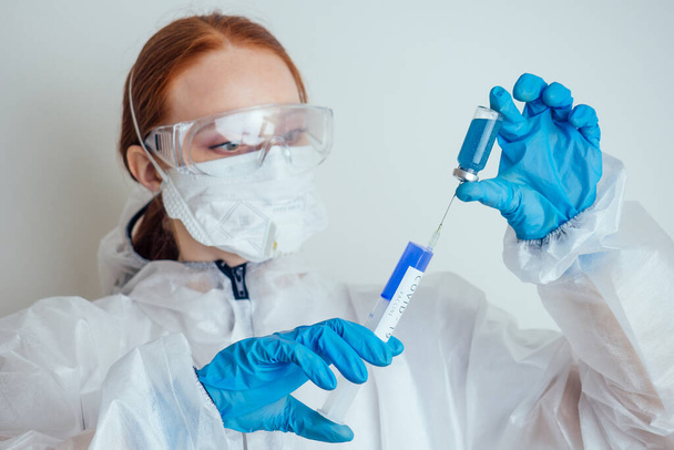 virologist woman in chemical protection mask ,glasses and gloves holding potential vaccine at the lab - Foto, immagini