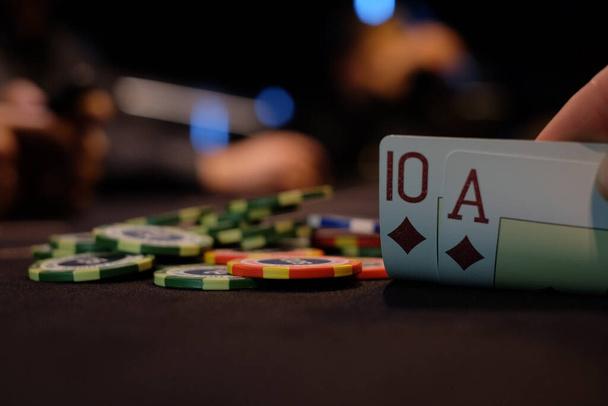 Dealer or croupier shuffles poker cards in a casino on the background of a table, chips. Concept of poker game, game business. Playing for money, a big win, a jackpot, gambling, a desire to get rich. - Foto, Imagen