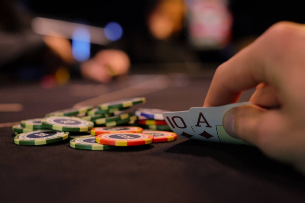 Dealer or croupier shuffles poker cards in a casino on the background of a table, chips. Concept of poker game, game business. Playing for money, a big win, a jackpot, gambling, a desire to get rich. - Foto, imagen