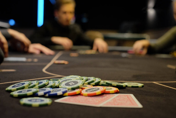 Dealer or croupier shuffles poker cards in a casino on the background of a table, chips. Concept of poker game, game business. Playing for money, a big win, a jackpot, gambling, a desire to get rich. - 写真・画像