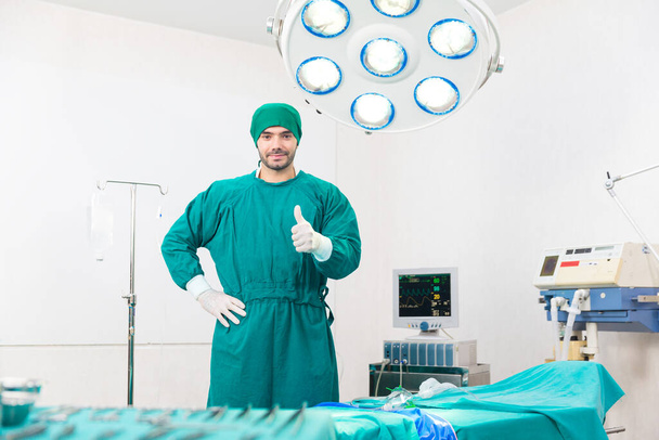 A sebész kesztyűt visel egy modern orvosi felszereléssel ellátott műtőben. A sebészek felemelik a hüvelykujjukat. A sebész orvosoknak kiváló hüvelykujjuk van.. - Fotó, kép