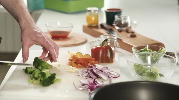 Profi-Koch schneidet grünen Brokkoli an Bord und legt Gemüse in Tasse. Vorbereitung einer vegetarischen Mahlzeit zum Mittag- oder Abendessen. Gesunde Ernährung Gemüsesalat. Essen mit scharfem Messer in Wohnküche aufgeschnitten - Filmmaterial, Video