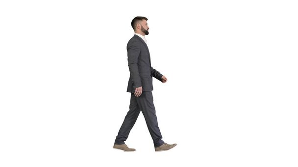 Serious businessman in formal suit walking on white background. - Foto, imagen