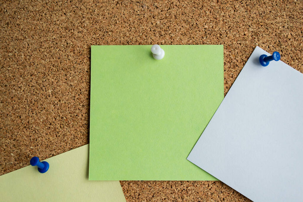 Trois notes de papier de couleur verte, blanche et jaune sur un panneau de liège, attaché avec une broche blanche. Espace de copie. - Photo, image