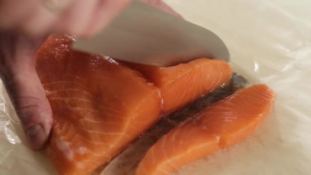 Taze balık pişiriyorum. Aşçı taze balık somonu veya alabalığı keskin çelik bıçakla ince dilimler halinde keser. Evdeki mutfakta yemek hazırlamak. Lezzetli deniz ürünleri. Üst görünüm - Video, Çekim