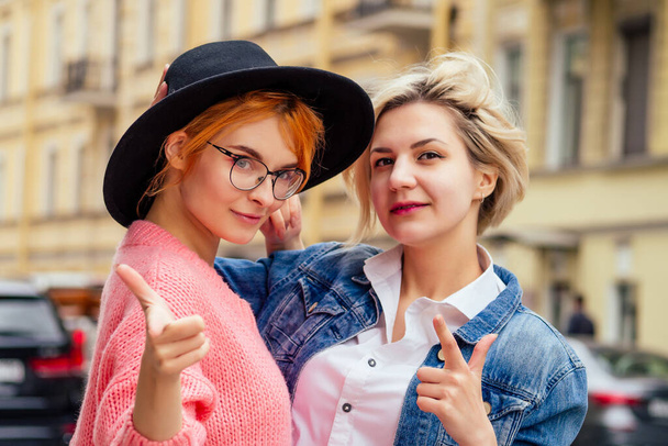redhaired young ginger woman feeling love to her blonde girlfriend in Europe streets - 写真・画像