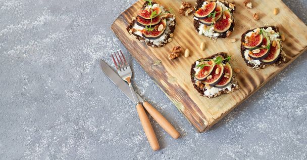 Zdrowe tosty z figami, miodem, serem i orzechami na wiejskiej drewnianej desce. Przestrzeń kopiowania - Zdjęcie, obraz