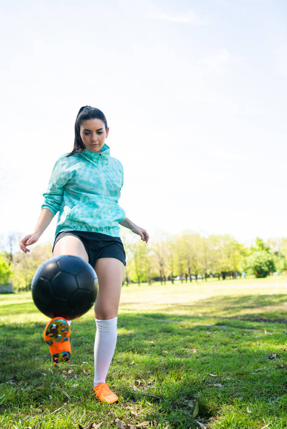 Portrait of young woman practicing soccer skills and doing tricks with the football ball. Soccer player juggling the ball. Sports concept. - Fotografie, Obrázek