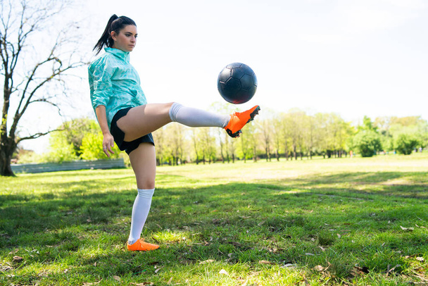 Portrait of young woman practicing soccer skills and doing tricks with the football ball. Soccer player juggling the ball. Sports concept. - Foto, afbeelding
