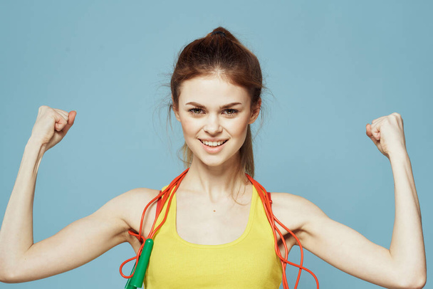 Woman with skipping rope sport exercise yellow tank top blue background - Foto, immagini