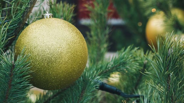 Großaufnahme große gelbe Weihnachtskugel auf grünem Kiefernholz. Neujahrsstimmung - Foto, Bild