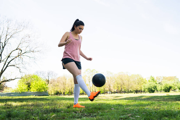 Portrait of young female soccer player training and practicing skills on football field. Sports concept. - 写真・画像