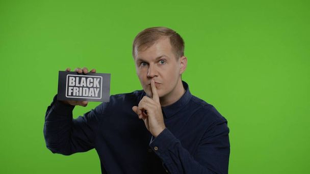 Άνθρωπος που δείχνει επιγραφή Μαύρη Παρασκευή, βάζοντας δάχτυλο στα χείλη κάνοντας χειρονομία σιωπής. Κλειδί χρωμίου - Φωτογραφία, εικόνα