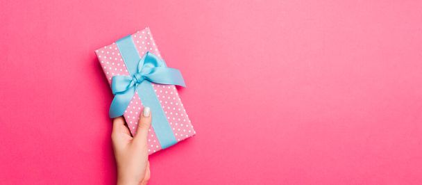 Girl Hands segurando caixa de presente de papel artesanal com como um presente para o Natal ou outro feriado no fundo rosa, vista superior com sppace cópia. - Foto, Imagem