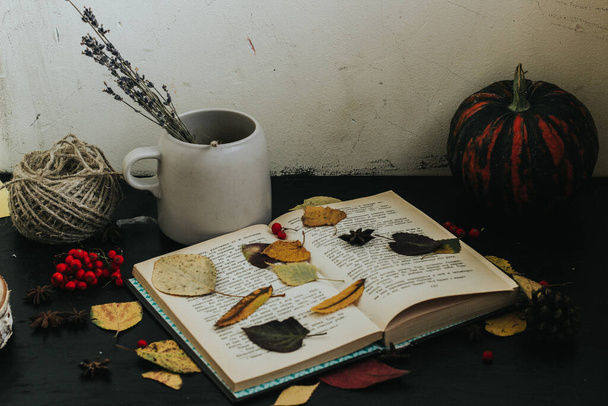 composition d'automne sur un fond sombre, atmosphère chaleureuse, thé, livres, feuillage - Photo, image