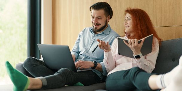 Photo of cheerful loving young couple using laptop and analyzing their finances with documents - Φωτογραφία, εικόνα
