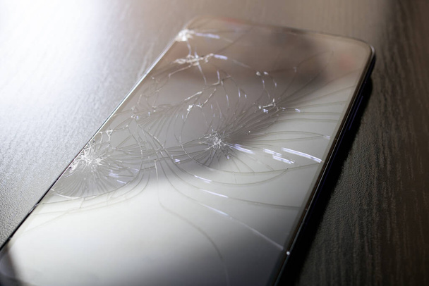 Broken mobile phone black display, cracks close up - Foto, Imagem