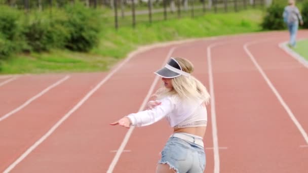 Красива молода блондинка танцює twerk на біговій доріжці стадіону. Ефективно рухає свою здобич. Повільний рух
 - Кадри, відео