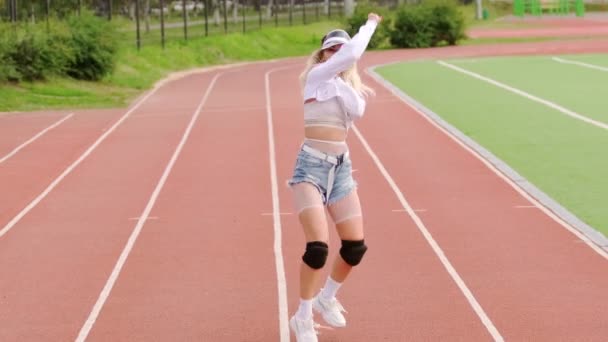 Schöne junge Blondine tanzt auf dem Laufband des Stadions. Wirkungsvoll bewegt sie ihre Beute. Zeitlupe - Filmmaterial, Video