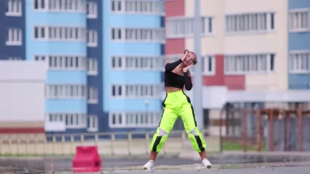 Wideo aktywnej młodej kobiety tańczącej hip-hop na świeżym powietrzu na tle wieżowców. Zwolniony ruch - Materiał filmowy, wideo