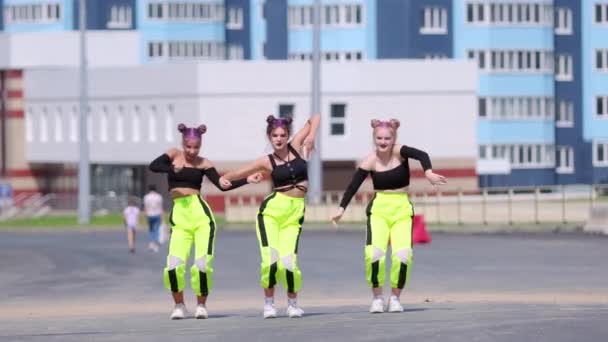Trzy młode piękne dziewczyny tańczą wolny styl street dancing, hip hop choreografia na zewnątrz na tle wieżowców budynków. Zwolniony ruch - Materiał filmowy, wideo
