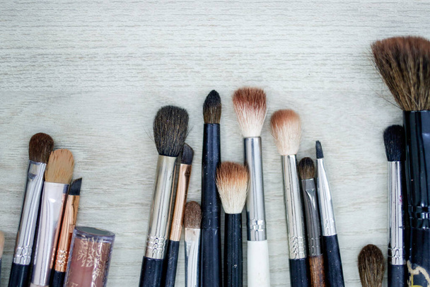 various brushes for production and misaligned makeup on wooden surface - Foto, Imagem