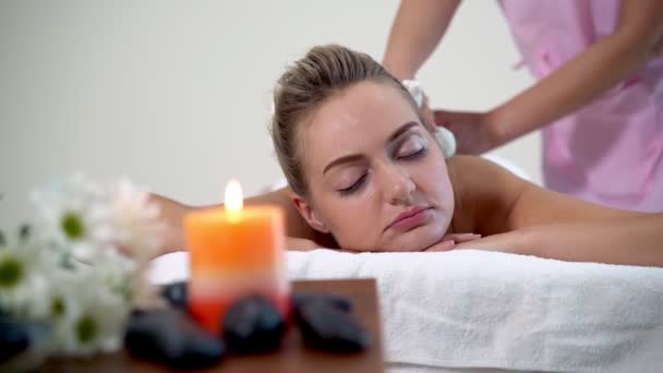 Massagetherapeutin mit Kräuterkompresse auf Frau. - Filmmaterial, Video