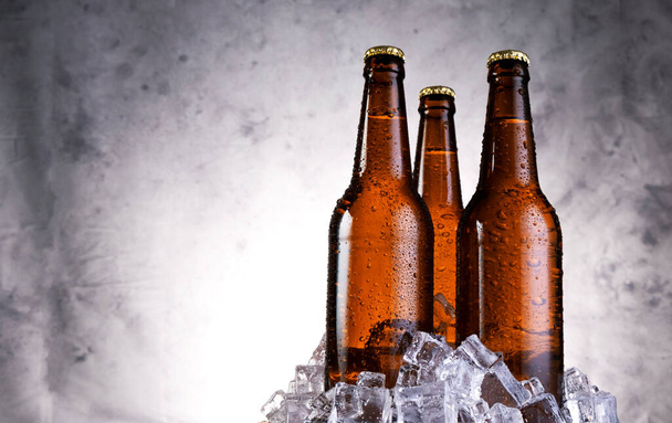 Su damlalı soğuk bira, gri arka planda buz küplü bira şişeleri. - Fotoğraf, Görsel